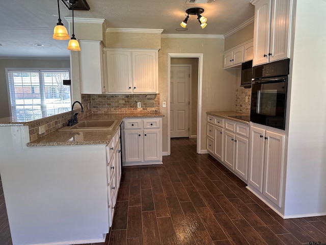 kitchen featuring oven, dark wood finished floors, ornamental molding, white cabinetry, and a sink