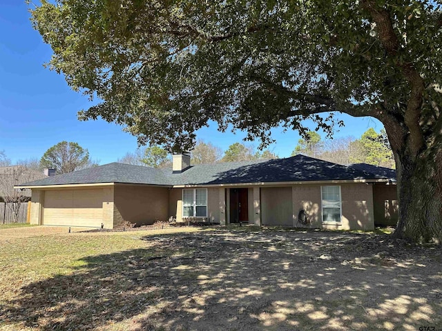 ranch-style house with brick siding, an attached garage, and a chimney