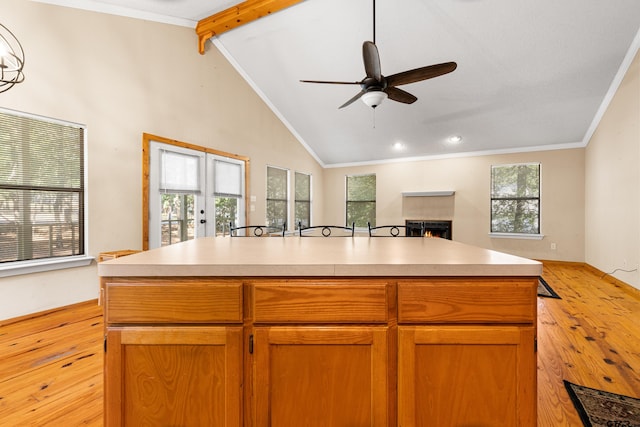 149 Primrose Path, Hawkins, TX 75765 - kitchen with light wood-style flooring, open floor plan, a lit fireplace, a ceiling fan, and crown molding
