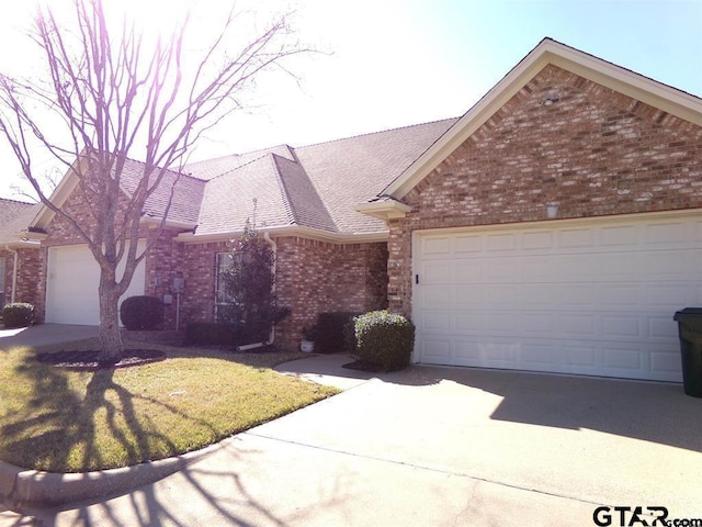 ranch-style house featuring brick siding, roof with shingles, an attached garage, driveway, and a front lawn