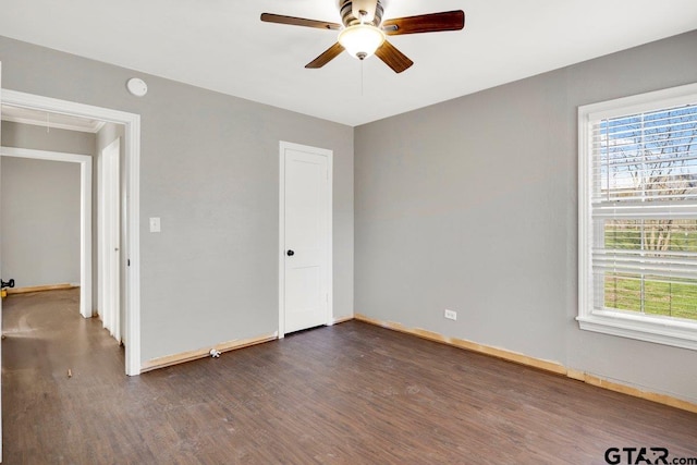 unfurnished bedroom featuring ceiling fan, dark wood-type flooring, attic access, and baseboards