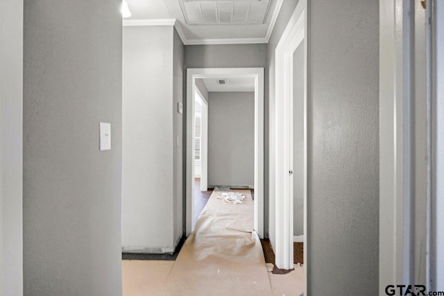 hallway featuring a textured wall, ornamental molding, and visible vents