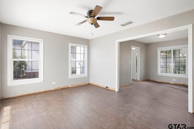 empty room featuring a ceiling fan, baseboards, visible vents, and wood finished floors