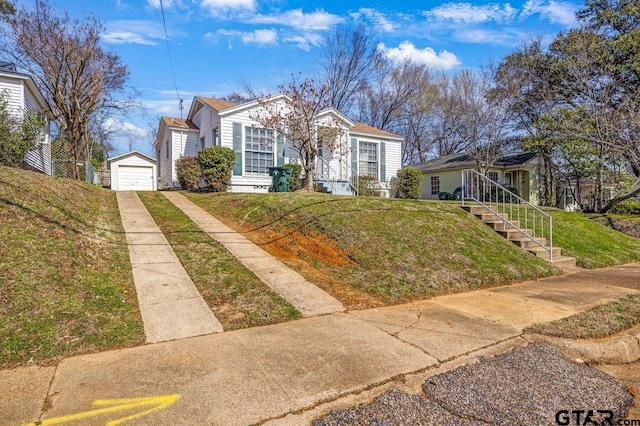 view of front facade featuring an outbuilding, a garage, stairs, driveway, and a front lawn