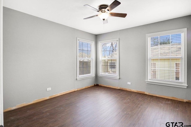 empty room featuring dark wood-style floors, ceiling fan, and baseboards