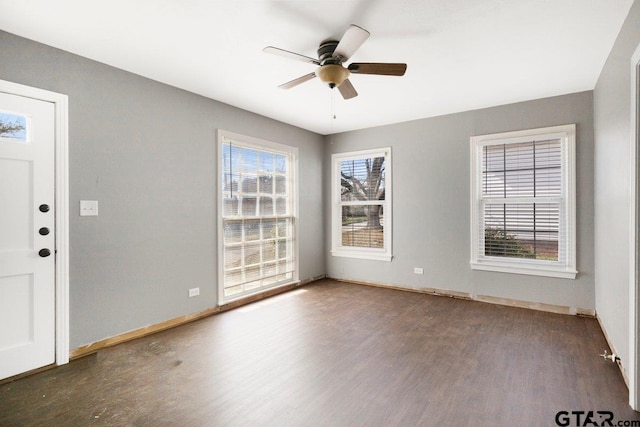 spare room featuring a healthy amount of sunlight, ceiling fan, and dark wood-style flooring