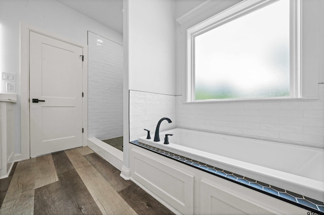 bathroom featuring wood-type flooring, separate shower and tub, and a wealth of natural light