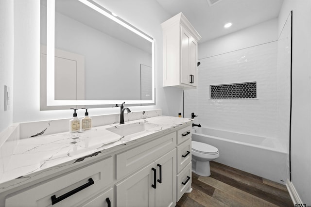 full bathroom with hardwood / wood-style flooring, shower / bathtub combination, vanity, and toilet