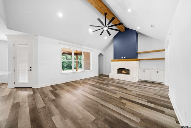 unfurnished living room with wood-type flooring, a brick fireplace, high vaulted ceiling, and beam ceiling