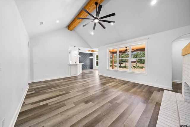 unfurnished living room with beamed ceiling, ceiling fan, and dark wood-type flooring