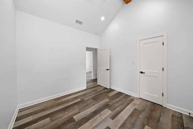 unfurnished bedroom featuring dark wood-type flooring and high vaulted ceiling