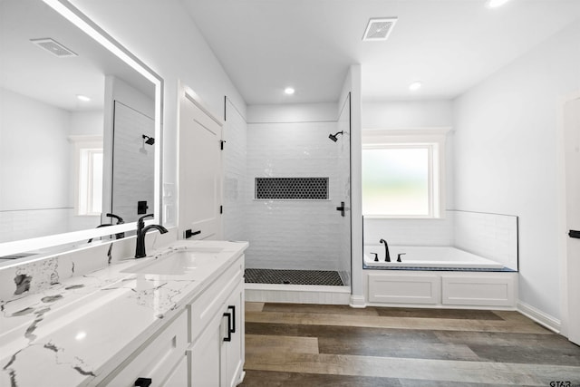 bathroom featuring wood-type flooring, shower with separate bathtub, and vanity