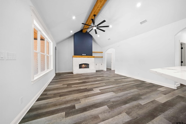 unfurnished living room with vaulted ceiling with beams, dark hardwood / wood-style floors, a brick fireplace, and ceiling fan