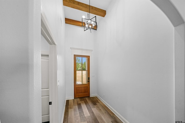 doorway featuring beamed ceiling, wood-type flooring, and a chandelier