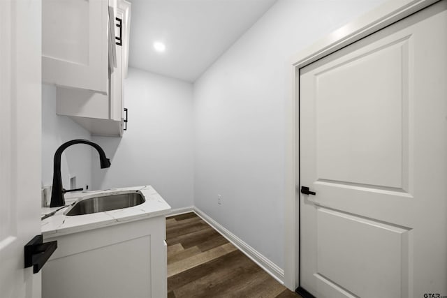 laundry room featuring dark hardwood / wood-style flooring, sink, and cabinets