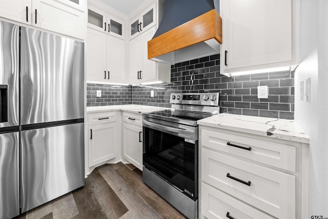 kitchen featuring stainless steel appliances, premium range hood, light stone countertops, and white cabinets