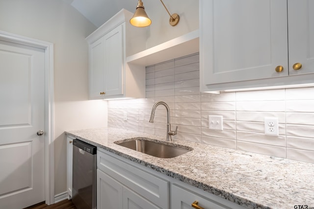 kitchen with light stone countertops, tasteful backsplash, sink, dishwasher, and white cabinetry