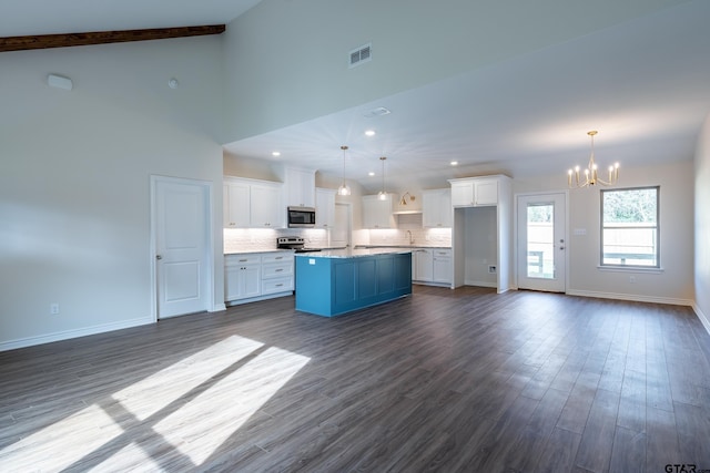 kitchen with appliances with stainless steel finishes, wood-type flooring, a notable chandelier, white cabinets, and a kitchen island