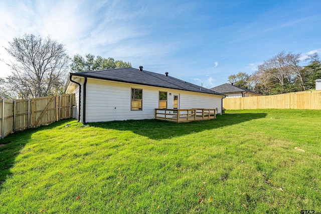 back of house featuring a wooden deck and a lawn