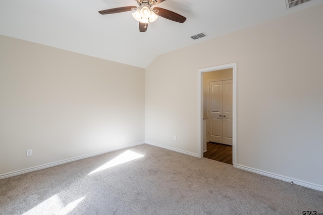 carpeted spare room featuring vaulted ceiling and ceiling fan