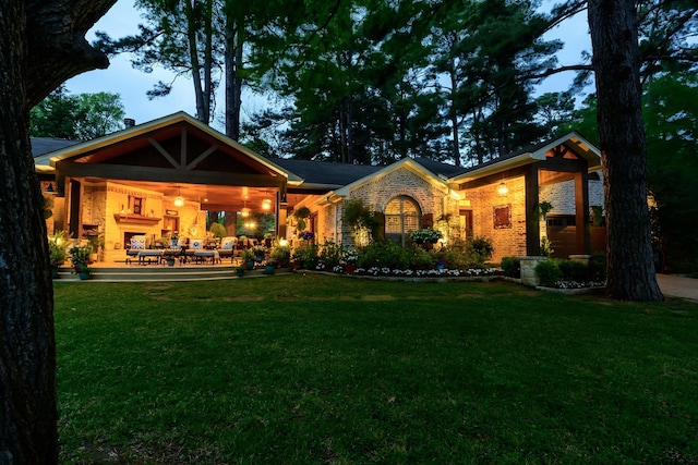 rear view of property featuring brick siding, a patio, outdoor lounge area, and a lawn