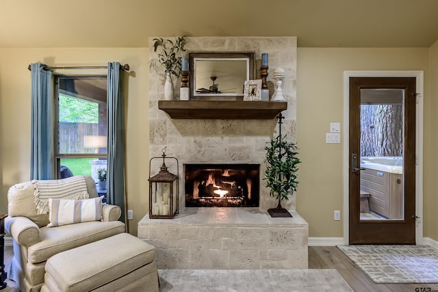 living area featuring baseboards, wood finished floors, and a tiled fireplace