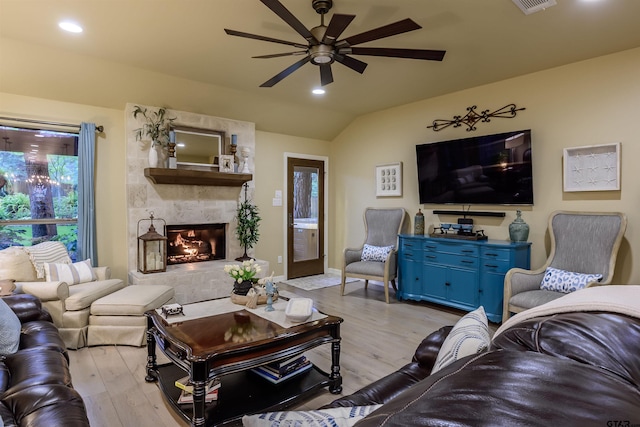 living room with vaulted ceiling, light wood-type flooring, a fireplace, and a ceiling fan