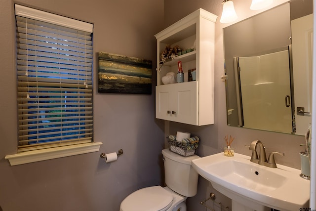 bathroom with toilet, a sink, and a shower with shower door