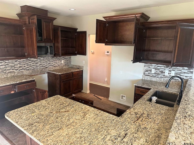 kitchen featuring decorative backsplash, sink, and light stone counters