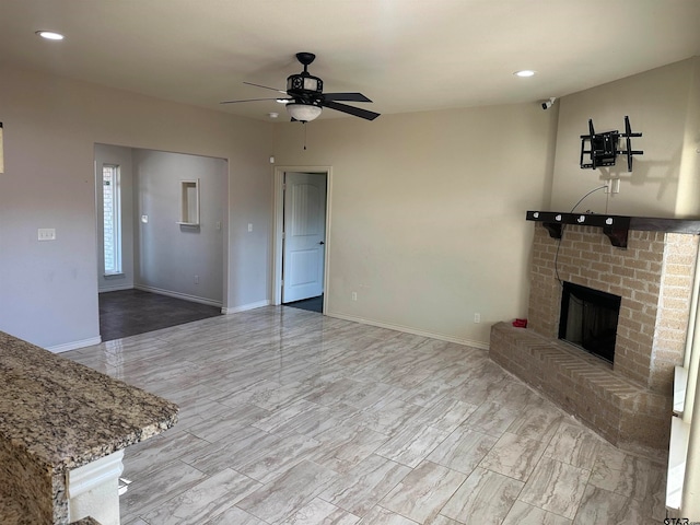 unfurnished living room with a brick fireplace and ceiling fan