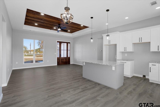 kitchen featuring a tray ceiling, white cabinetry, hardwood / wood-style flooring, and ceiling fan