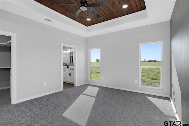 unfurnished bedroom featuring a walk in closet, a tray ceiling, wooden ceiling, connected bathroom, and a closet