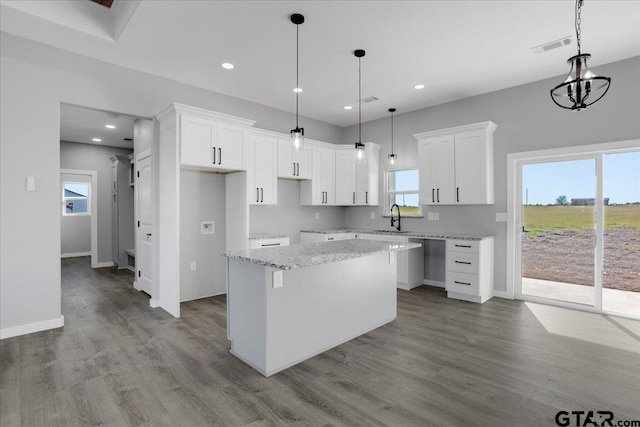 kitchen with light stone counters, sink, light hardwood / wood-style flooring, white cabinets, and a center island