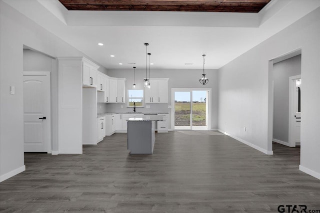 kitchen featuring pendant lighting, white cabinets, hardwood / wood-style flooring, light stone countertops, and a kitchen island