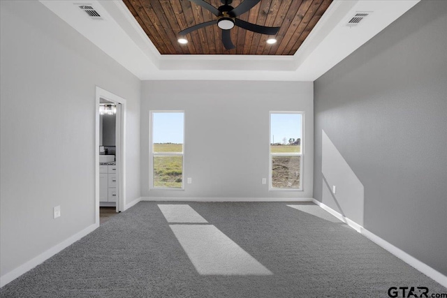 carpeted spare room featuring a raised ceiling, ceiling fan, and wooden ceiling