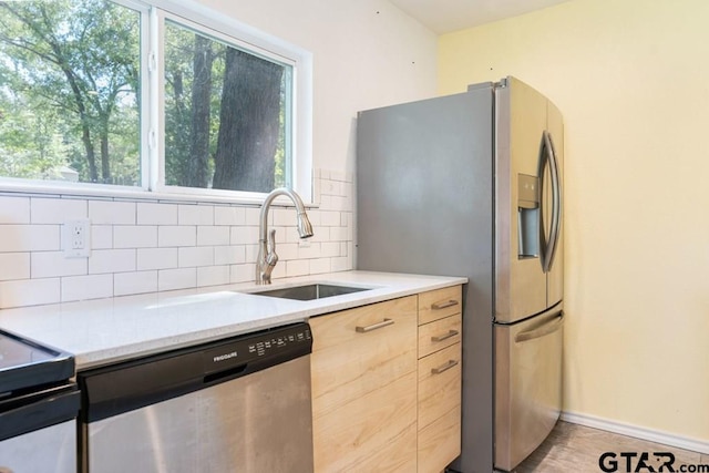 kitchen with backsplash, stainless steel appliances, light brown cabinets, sink, and light tile patterned flooring