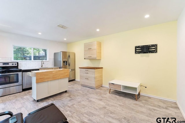 kitchen featuring stainless steel appliances, light hardwood / wood-style floors, light brown cabinetry, and butcher block counters