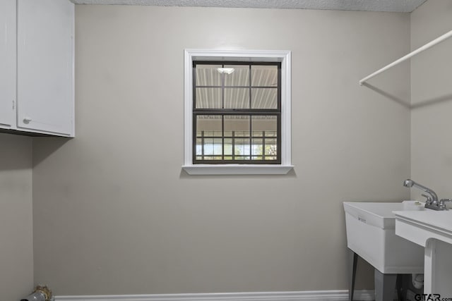 laundry room featuring cabinets and a textured ceiling