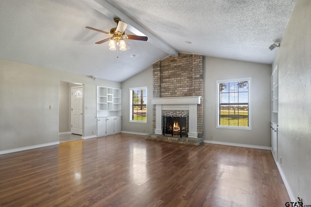 unfurnished living room featuring hardwood / wood-style floors, vaulted ceiling with beams, a brick fireplace, and plenty of natural light