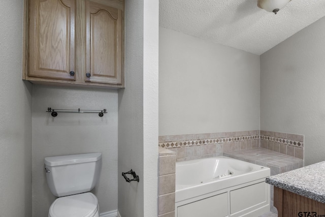 bathroom featuring vanity, a textured ceiling, a tub to relax in, and toilet