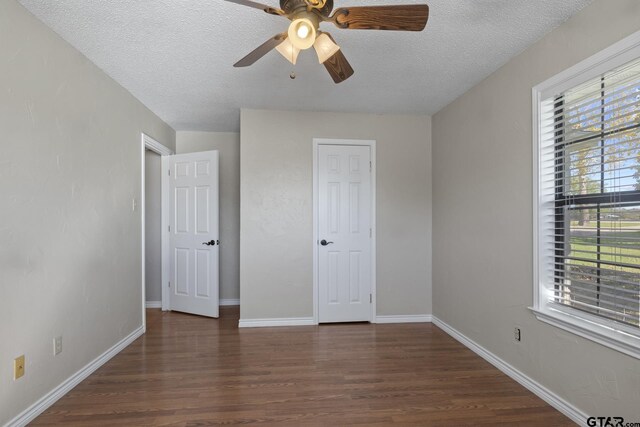 unfurnished bedroom featuring a textured ceiling, multiple windows, ceiling fan, and dark hardwood / wood-style floors