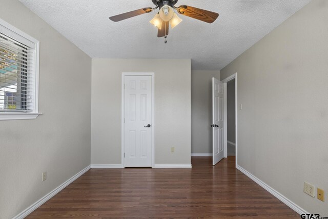 unfurnished bedroom featuring ceiling fan, dark wood-type flooring, and a textured ceiling