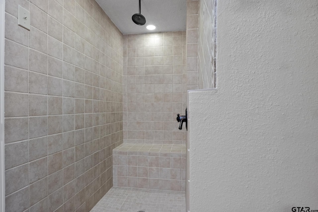 bathroom with tiled shower and a textured ceiling