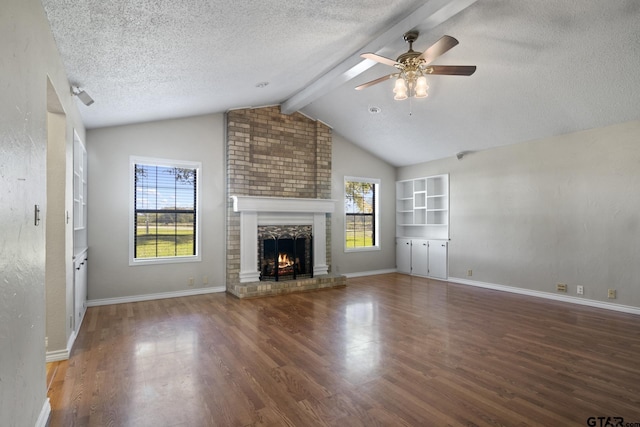 unfurnished living room with dark hardwood / wood-style floors, ceiling fan, vaulted ceiling with beams, a textured ceiling, and a fireplace