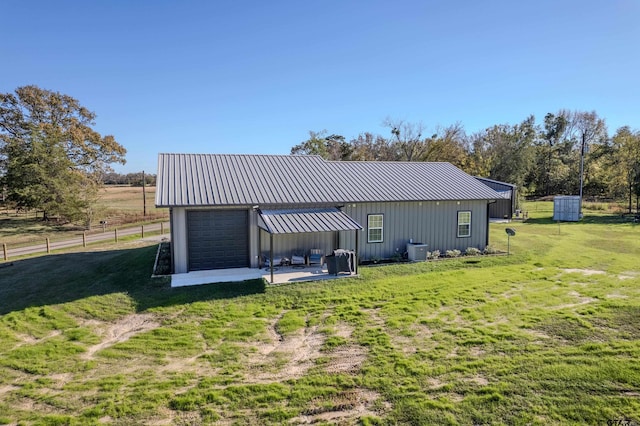 exterior space featuring central AC unit, a garage, a lawn, and an outdoor structure