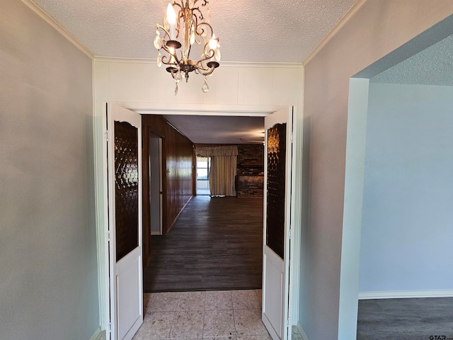 hall with light wood-type flooring, a textured ceiling, and crown molding