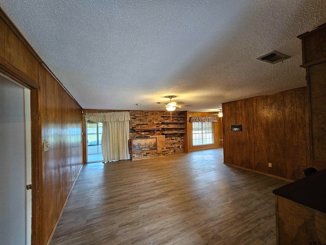 unfurnished living room with hardwood / wood-style floors, wooden walls, and a textured ceiling