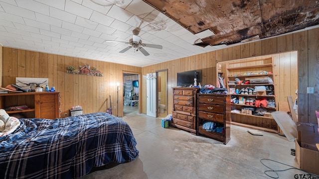 bedroom featuring ceiling fan, concrete floors, and wooden walls