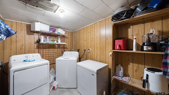 laundry area with wooden walls and washer and clothes dryer