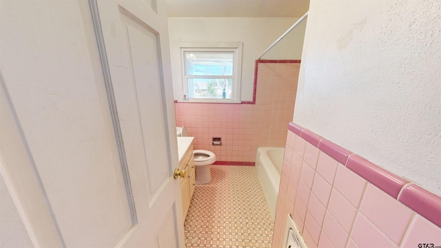 full bath featuring toilet, a wainscoted wall, vanity, tile walls, and tub / shower combination